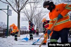 Punëtorët e qytetit pastrojnë borën në një shteg pranë Qytetit të Ndaluar pas një reshje bore në Pekin të Kinës, 11 dhjetor 2023.