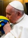 Папа Римський Франциск цілує прапор України зі знищеного армією РФ українського села, який йому подарували разом і браслетом із металу з «Азовсталі» та пачкою солі з останньої партії комбінату «Артемсіль». Ватикан, 24 лютого 2023 року