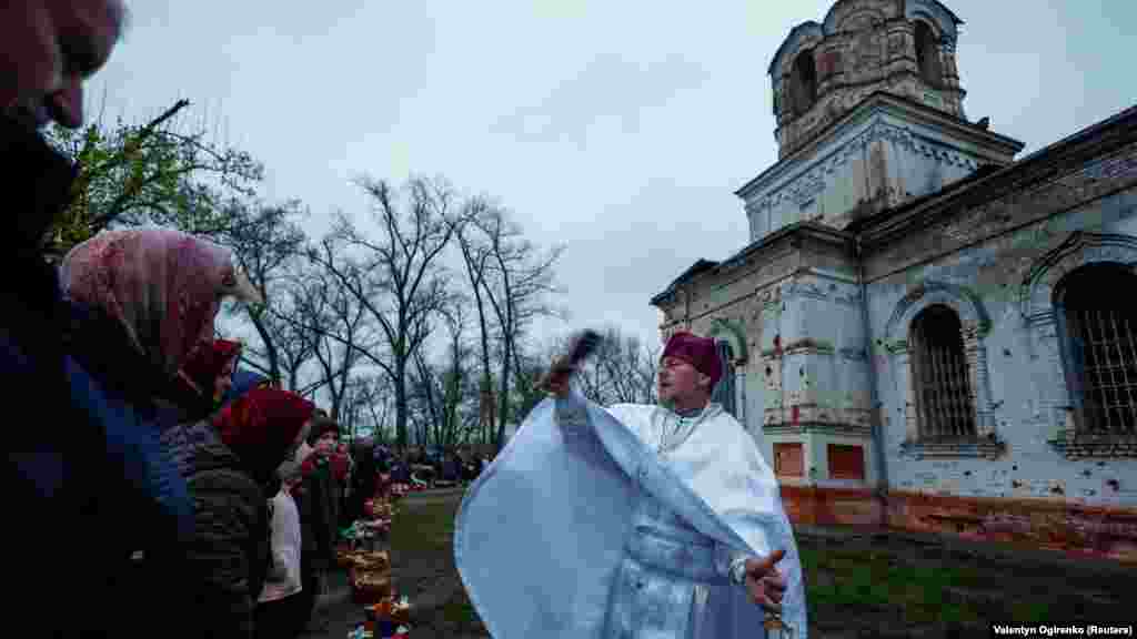 Szerhij atya szentelt vízzel locsolja meg a hívőket a templom előtt