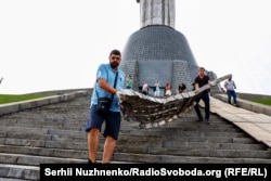 Рабочие выносят часть демонтированного герба СССР со щита монумента «Родина-мать». Киев, Украина, 30 июля 2023 года