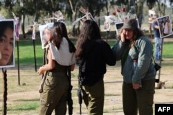 Израильские солдаты перед фотографиями людей, взятых в плен или убитых боевиками во время музыкального фестиваля Supernova 7 октября на юге Израиля.