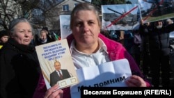 Жена държи книжка с посланията на руския президент Владимир Путин през 2023 г. и лист с надпис на руски език: "Ние помним".