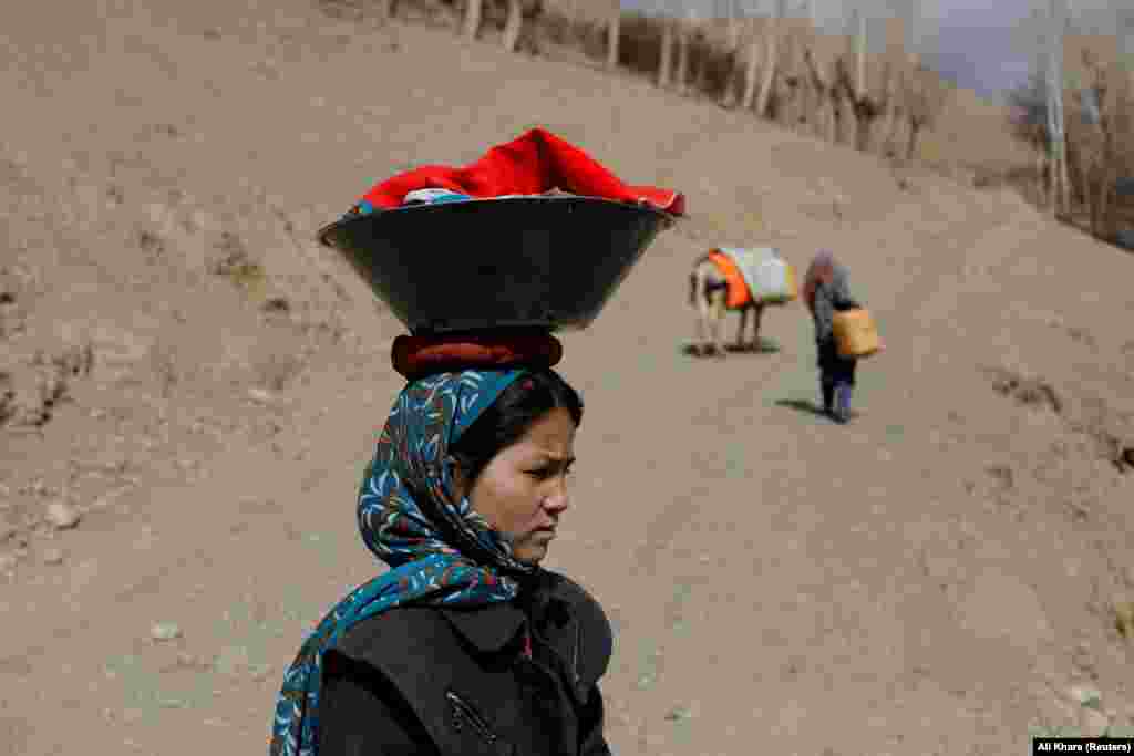 An Afghan girl carries washed clothes on her head in Bamiyan.