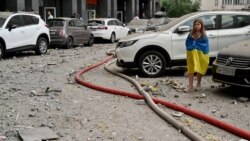 Девочка возле 24-этажного здания, частично разрушенного в результате ракетного удара в Киеве