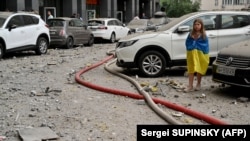 Девочка возле 24-этажного здания, частично разрушенного в результате ракетного удара в Киеве