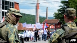 Austrijske mirovne snage NATO stoje dok zaposleni u lokalnoj bolnici predvode protestni marš kosovskih Srba od centra Mitrovice ka opštini Zvečan, na severu Kosova, 19. juna 2023. godine.