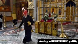 An Orthodox priest collects religous objects as others clear up glass and debris inside the Holy Intercession Cathedral, which was damaged by missile strikes in Zaporizhzhya on October 18.