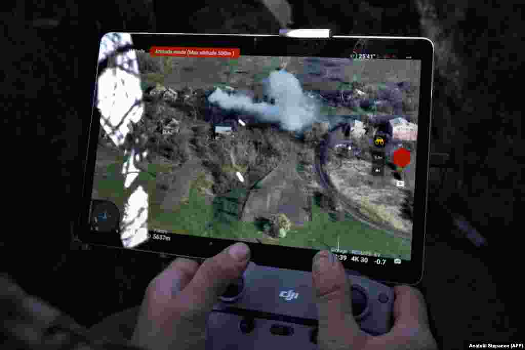 A drone operator watches as clouds of smoke rise above burning Russian targets near the eastern city of Bakhmut on April 16. Videos showing Ukrainian drone operators dropping grenades on Russian soldiers or even into the hatches of their armored vehicles have circulated widely on social media.