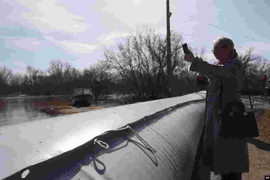 A woman takes a photo of floodwaters behind a rubber dam in Orenburg as water levels on the Ural River reached 11.29 meters, up from 10.87 meters on April 11, a record high. &nbsp;