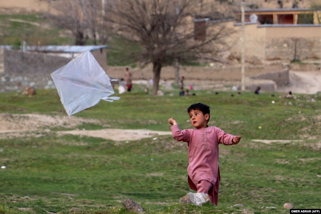 Një djalë fluturon një balonë në një fushë në rrethin Fayzabad të provincës Badakhshan.