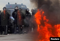 Francuski žandari i interventna policija stoje na poziciji blizu požara na Place de la Concorde u blizini Narodne skupštine gdje su se okupili demonstranti nakon što je francuska premijerka najavila upotrebu člana 49.3, posebne klauzule u francuskom Ustavu, u Parizu, 16. marta 2023.