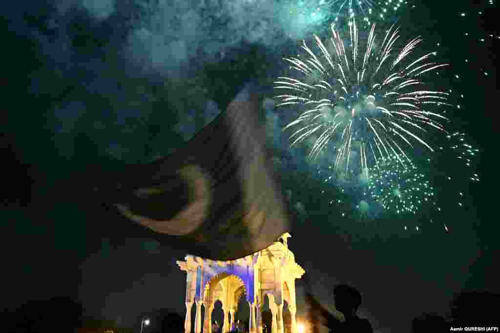 A man waves a flag as fireworks explode over Islamabad as part of the Independence Day celebrations ahead of the country&#39;s 76th Independence Day, in Islamabad.