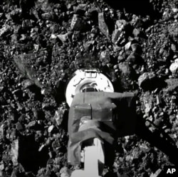 На тази снимка от видеоклип, публикуван от НАСА, космическият апарат Озирис-Рекс докосва повърхността на астероида Бенну във вторник, 20 октомври 2020 г.