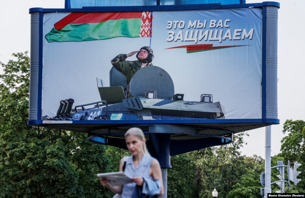 Një grua duke ecur pranë një pllakati promovues për forcat e armatosura të Bjellorusisë, në Minsk.