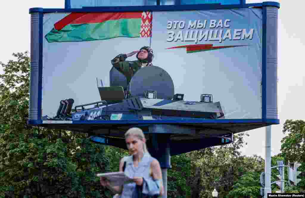 A woman walks past a billboard in Minsk promoting Belarus&#39;s armed forces.