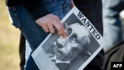 Плакат с карикатурой на Владимира Путина в руке участницы акции протеста против агрессии в отношении Украины. Берлин, лето 2022 года
