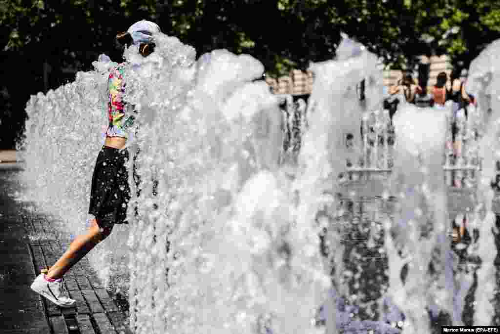 A girl cools off in a fountain in central Budapest.