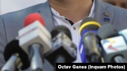 Imagine de arhivă: microfoane de televiziune plasate pe pupitrul unui politician în timpul unei conferință de presă.