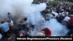 Armenia - Demonstrators react to stun grenades fired by police during a protest against Armenian Prime Minister Nikol Pashinian in Yerevan, June 12, 2024.