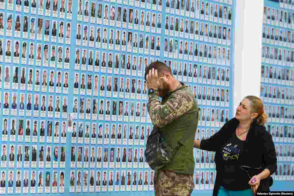 A Ukrainian soldier reacts next to the memory wall of fallen defenders of the country in Kyiv.