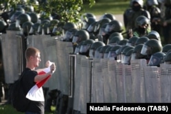Сторонник оппозиции и сотрудники правоохранительных органов во время акции протеста. Минск, 2020 год