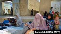 Burkába öltözött afgán nők árulnak ruhát egy kandahári utcán 2023. március 7-én