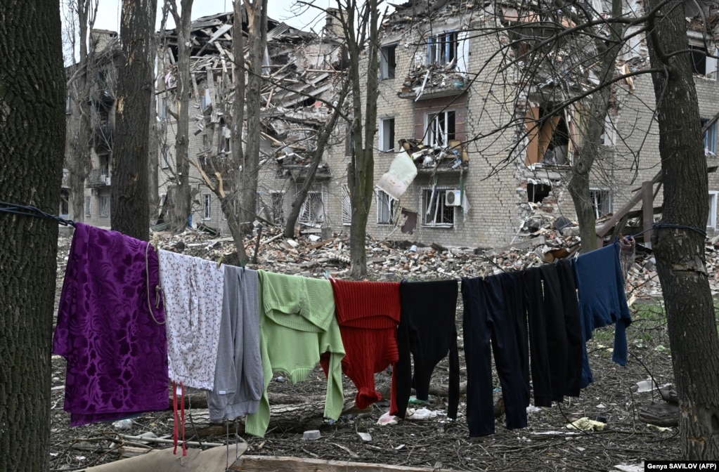 Rroba të varuar pranë një ndërtese banimi të shkatërruar në Avdivka.