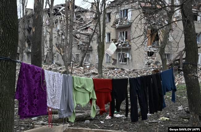 Rroba të varuar pranë një ndërtese banimi të shkatërruar në Avdijivka.