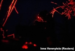 Украинский военный управляет дроном ночью, используя красный фонарь для маскировки