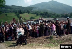 Holandski mirovnjaci UN-a čuvaju neke od 20.000 muslimanskih izbjeglica iz Srebrenice koje čekaju prevoz iz Potočara u Kladanj kod Olova, koji je bio pod kontrolom tadašnje Armije Republike BiH, 12. jula 1995.