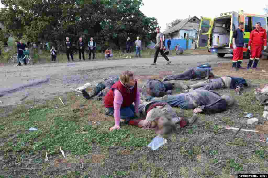 Жінка плаче біля тіл загиблих після удару в селі Гроза Харківської області 5 жовтня 2023 року. За останніми даними ДСНС, у результаті російської атаки загинула 51 людина, в тому числі 6-річний хлопчик
