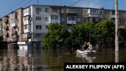 Ukrainian security forces transport local residents in a boat during an evacuation from a flooded area in Kherson on June 7.