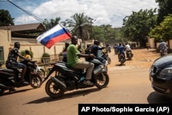 Susținători ai căpitanului Ibrahim Traore defilează cu un steag rusesc pe străzile din Ouagadougou, Burkina Faso, 2 octombrie 2022. Se spune că trupele Wagner sunt folosite de autorități în schimbul exploatării unei mine