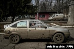 Un bărbat așteaptă într-o mașină avariată, în satul Chasiv Yar din Ucraina, 11 martie 2023.