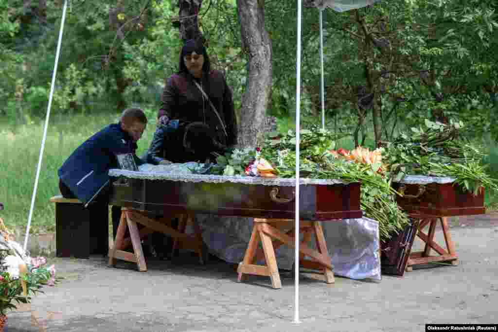 Oleh and Olha Aksenčenko pored kovčega sa telima njihovih 14-godišnjih kćerki, blizanki Ane i Julije, koje su ubijene u ruskom napadu na restoran u Kramatorsku, Ukrajina