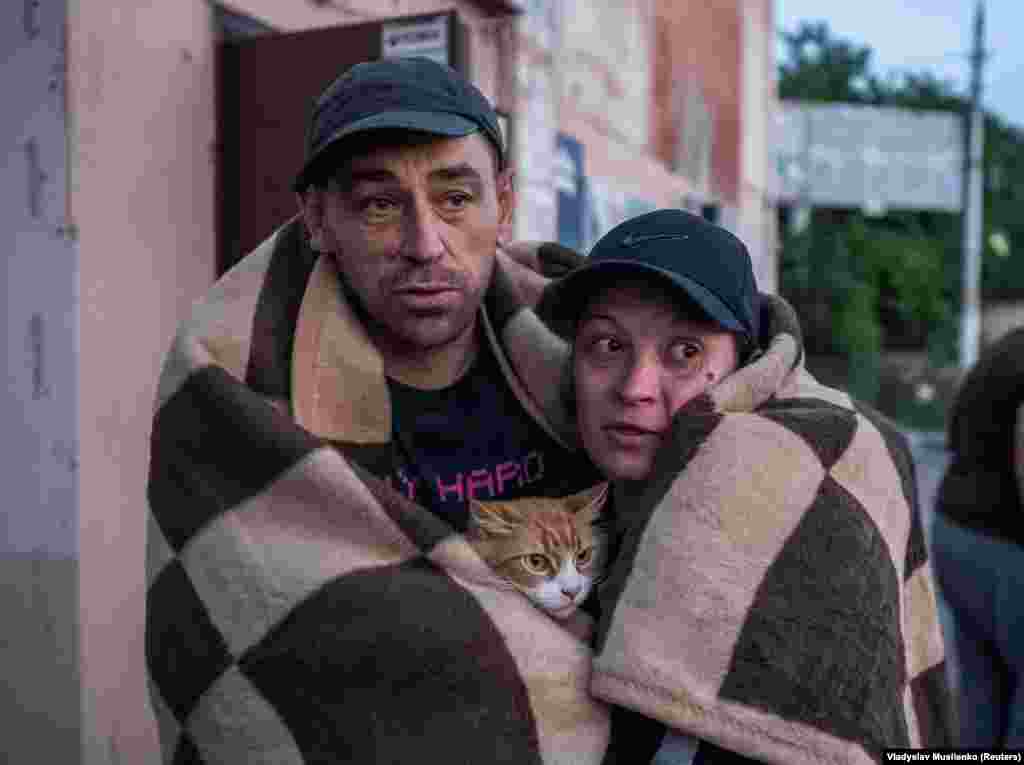 A couple and their cat huddle to stay warm after their evacuation.