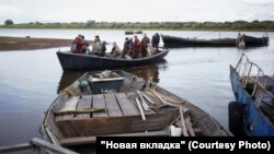 Вытащенная неводом рыба складывается в трюмы на моторных лодках, закрытые досками