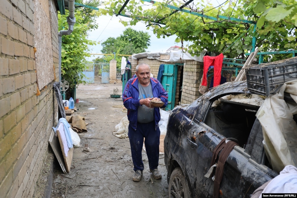 Микола на своєму подвір’ї біля пошкодженої внаслідок обстрілу автівки