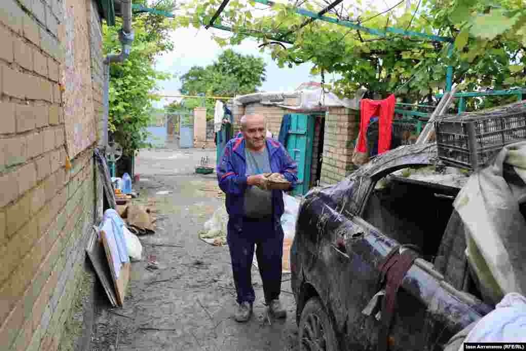 Микола на своєму подвір&rsquo;ї біля пошкодженої внаслідок обстрілу автівки