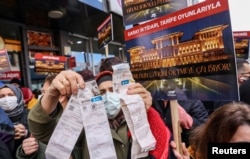 Участница акции протеста против увеличения цен на отопление и электроэнергию в Стамбуле показывает полученные ею счета. Февраль 2022 года. Фото: Reuters.