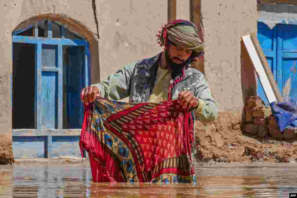 Një burrë afgan duke pastruar një copë në oborrin e tij që është përmbytur pas reshjeve të mëdha në distriktin Guzara të provincës Herat më 13 mars. Të paktën 60 njerëz kanë humbur jetën nga shiu dhe bora e madhe në Afganistan gjatë tri javëve të fundit.