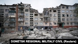 A man looks up at a residential building damaged by a Russian military strike in Slovyansk, Donetsk region, on April 14.