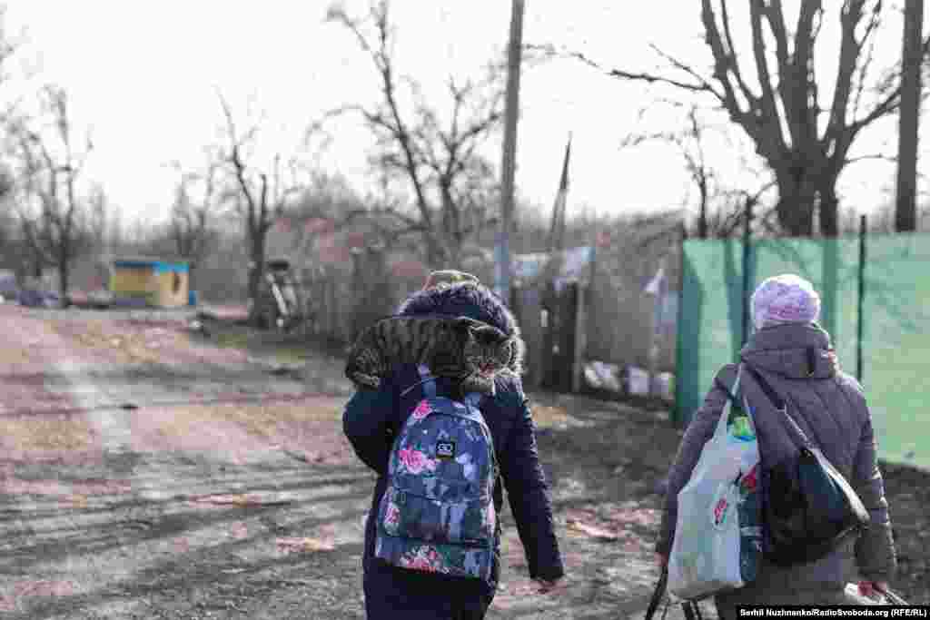 Кіт сидить на плечі дитини, яку разом з мамою евакуйовують із села Рудницьке, Київщина, березень 2022 року / Праворуч: та ж вулиця у березні 2024 року
