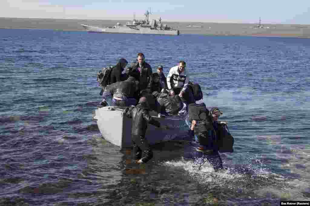 Crew members of the Ukrainian naval warship Konstantin Olshansky, which was blockaded by Russian warships, arrive on shore after leaving their ship on March 23. The ship was later seized and incorporated into the Russian Navy.&nbsp;