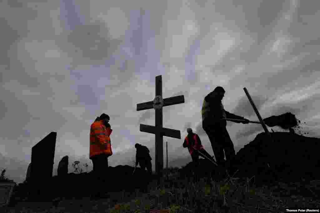 Чоловіки продовжують копати могили для загиблих від російського ракетного обстрілу в селі Гроза Харківської області й пізно ввечері