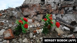 A makeshift memorial for civilian residents killed in Russian attacks is seen near a destroyed residential building in Izyum on February 20.