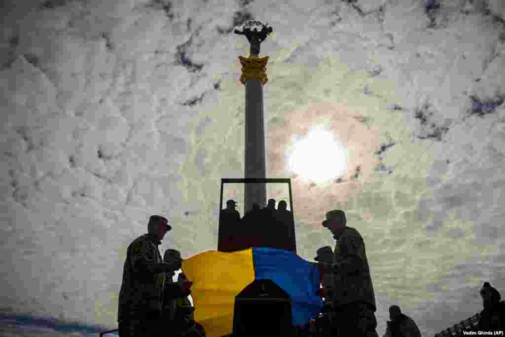 Ushtarë ukrainas duke vendosur flamurin kombëtar në arkivolin e një bashkëluftëtari të rënë, gjatë një ceremonie në Sheshin e Pavarësisë, në Kiev, më 5 prill.