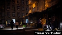 În fotografie, oameni din Kiev care se deplasează cu ajutorul unor dispozitive de iluminat, în preajma unui supermarket din Kiev, în urma unei pene de curent, în 16 mai 2024. Imagine cu caracter ilustrativ.