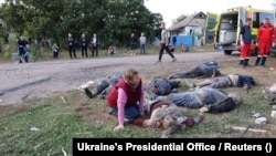 Žena kleči pored tijela ubijenih i povrijeđenih ljudi u ruskom raketnom napadu na selo Hroza u regiji Harkiv, Ukrajina, 5. oktobar 2023.