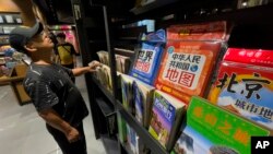 Čovjek u knjižari u Pekingu pored nove karte Kine i svijeta, koja je izazvala polemike, septembar 2023.